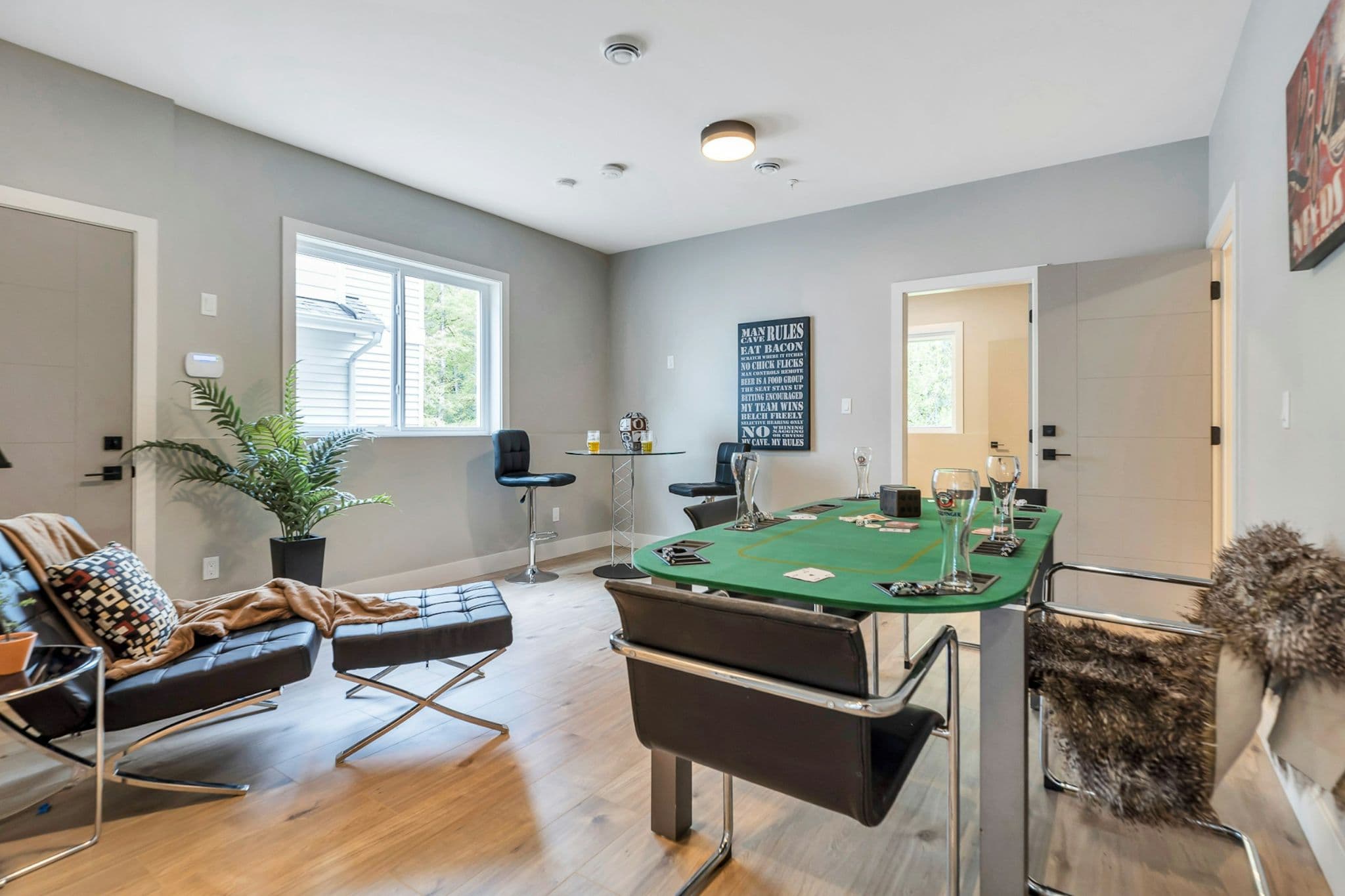 Emerald Ridge – Entertainment room with green poker table felt top, black leather accent chairs, ottoman, and pub-style seating.