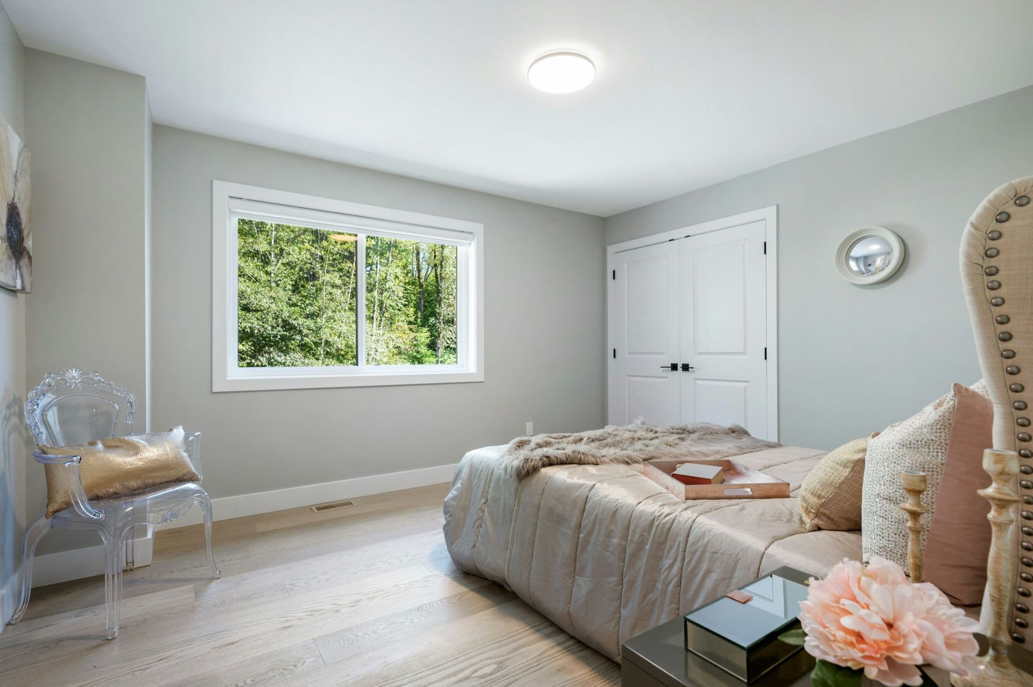 Emerald Ridge – Bedroom interior with acrylic transparent ghost chair, upholstered headboard bed, and double closet doors.