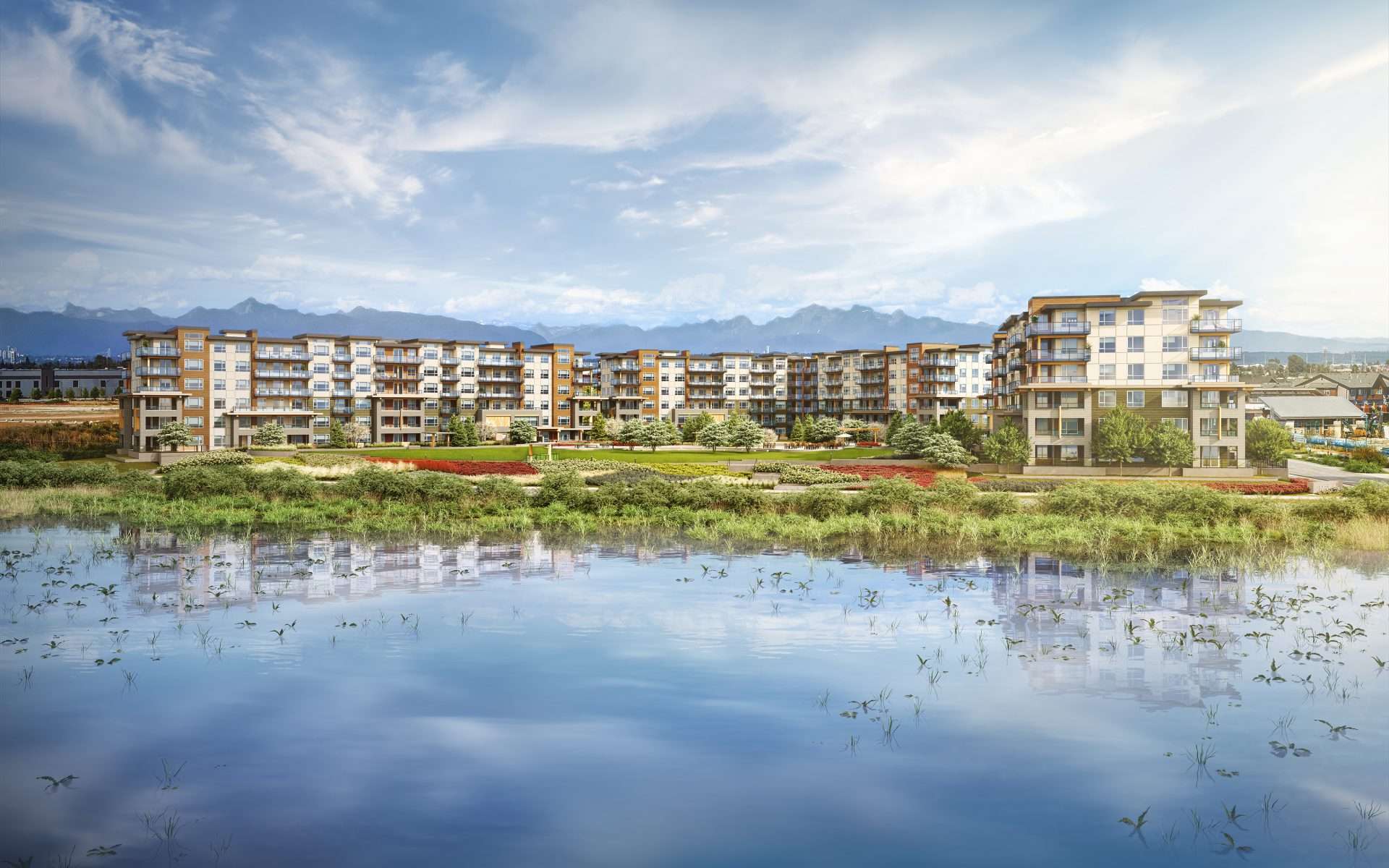 Salt and Meadow – A large multi-building mid-rise condo complex with mountain views behind, seen across a wetland pond with reflections and landscaped grounds in front.