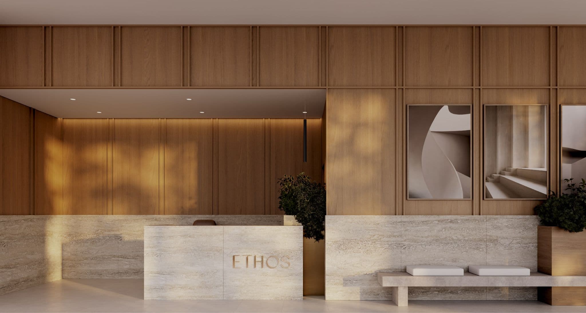 Ethos – A sophisticated residential lobby features a stone-clad reception desk engraved with the word ETHOS, backed by warm wood wall paneling. Warm, dappled sunlight illuminates the minimalist space, which includes a matching stone bench with white cushions and framed abstract artwork on the wall.