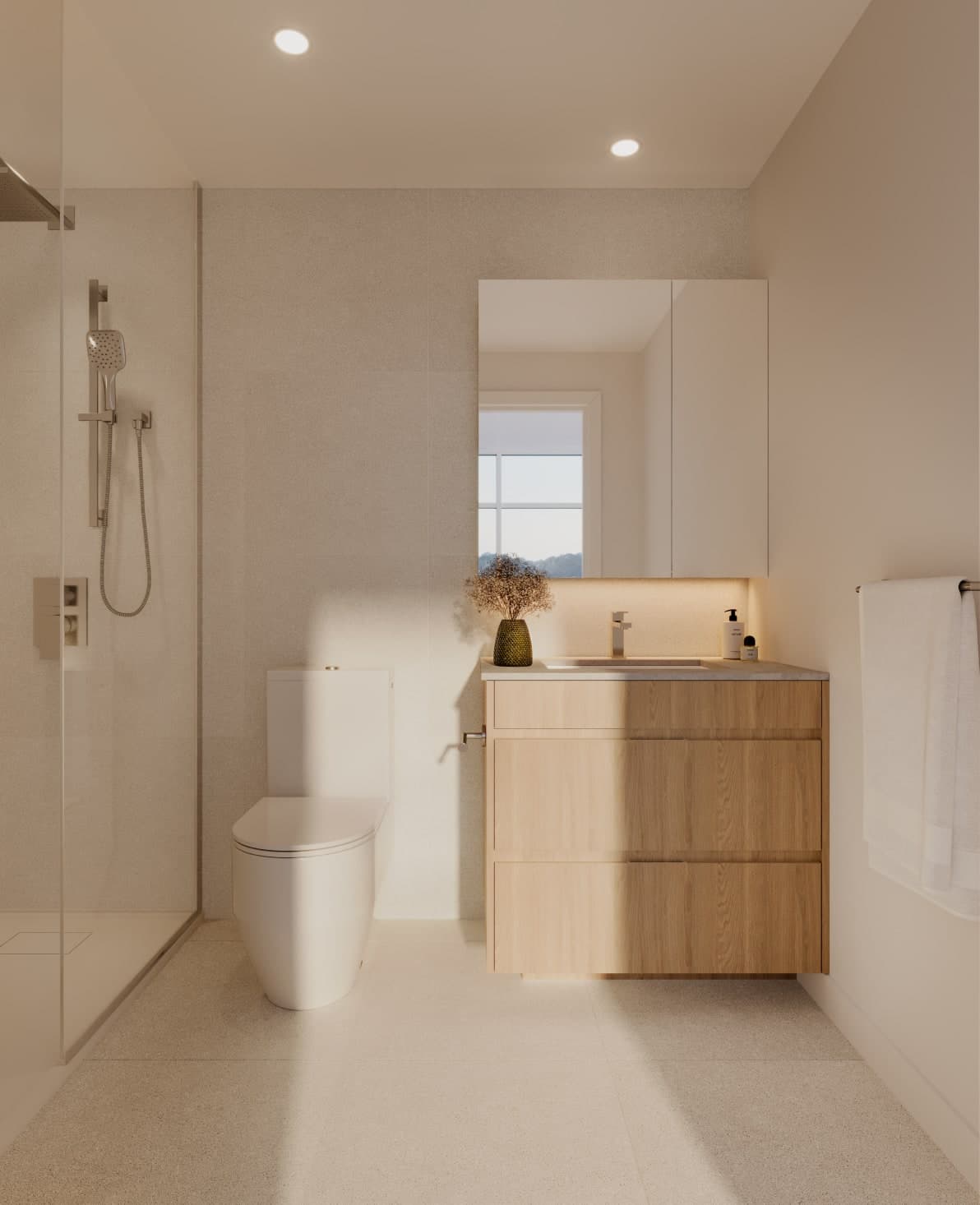 Ethos – A modern, minimalist bathroom with a light wood vanity, a glass-enclosed walk-in shower, and off-white tiled walls and floors. Warm, soft sunlight streams across the toilet and vanity, creating a serene and clean atmosphere.