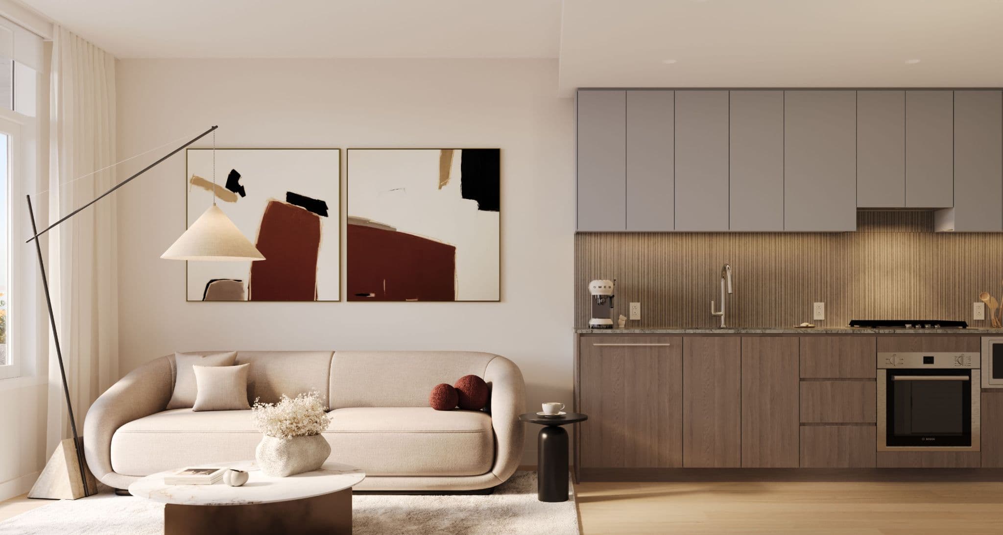 Ethos – An open-concept living area and kitchen styled in warm modern tones, featuring a curved beige sofa beneath framed abstract artwork and a sleek kitchen with grey flat-panel cabinets, dark wood lower cabinetry, and under-cabinet lighting. Natural daylight streams in from a side window, highlighting the marble coffee table, minimalist floor lamp, and light wood flooring.
