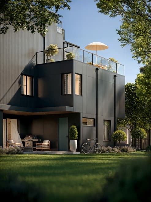 Katsura – A ground-level view of a modern multi-story townhouse clad in dark charcoal panels and vertical siding, featuring a private ground-floor patio with a BBQ grill and a rooftop terrace with a patio umbrella. The building faces a lush green lawn bordered by manicured shrubs, small trees, and a parked bicycle under bright daytime sunlight.
