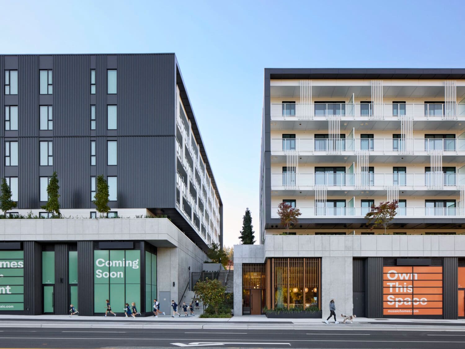 Moody Yards – A street-level rendering of two dark and light mid-rise buildings with balconies, ground-floor retail marked 'Coming Soon' and 'Own This Space', and a person walking a dog.
