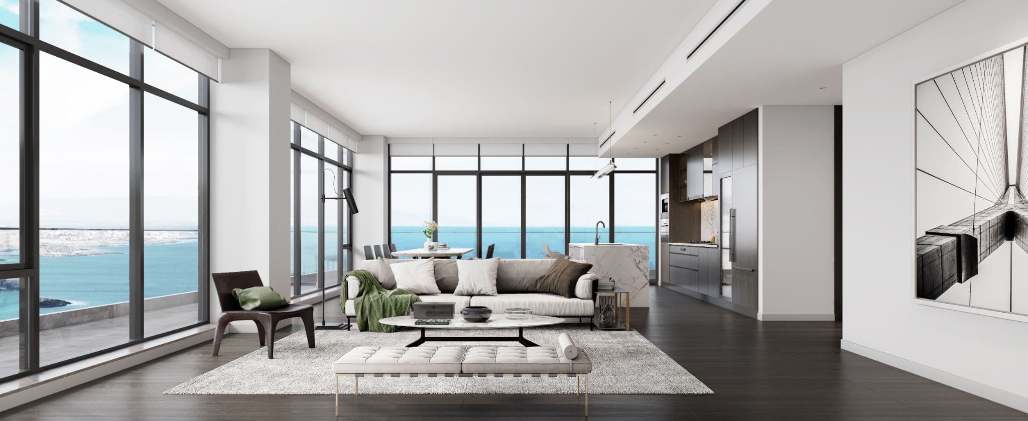Rodgers Creek One – A bright, open-concept luxury penthouse featuring a modern living room, dining area, and sleek kitchen with dark wood cabinetry and a marble waterfall island. Floor-to-ceiling windows wrap around the space, offering sweeping panoramic views of the open ocean and coastline under clear daylight.