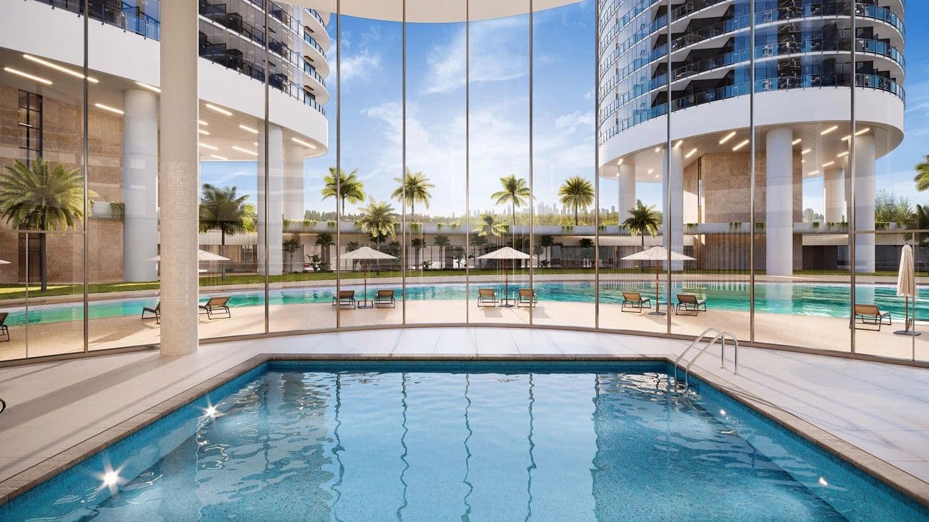 Circle at Concord Brentwood – Rendering of an outdoor pool deck with lounge chairs, umbrellas, and palm trees, framed by floor-to-ceiling glass and the towers above.