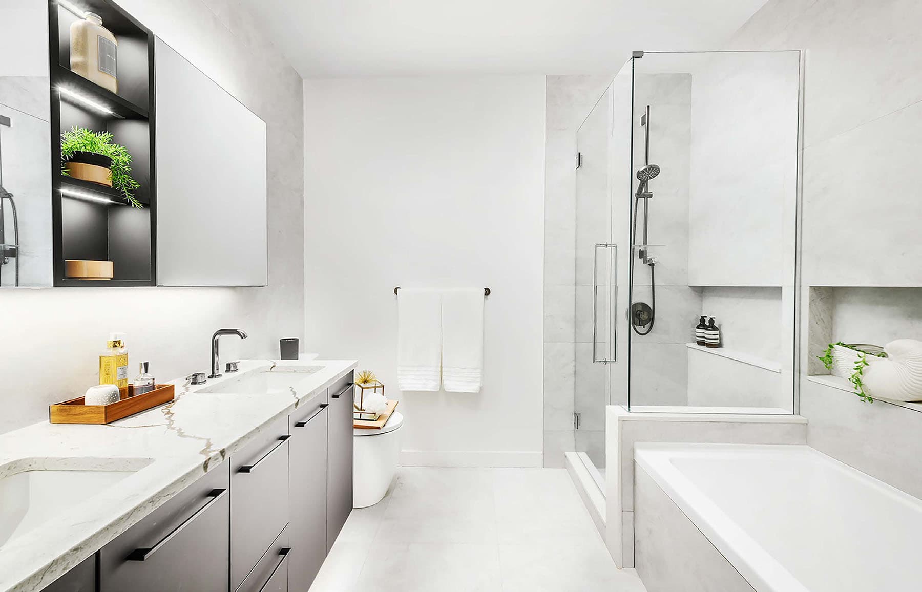 Circle at Concord Brentwood – Bathroom with a long double vanity, backlit mirrored cabinet, a glass-enclosed shower, and a separate soaking tub.