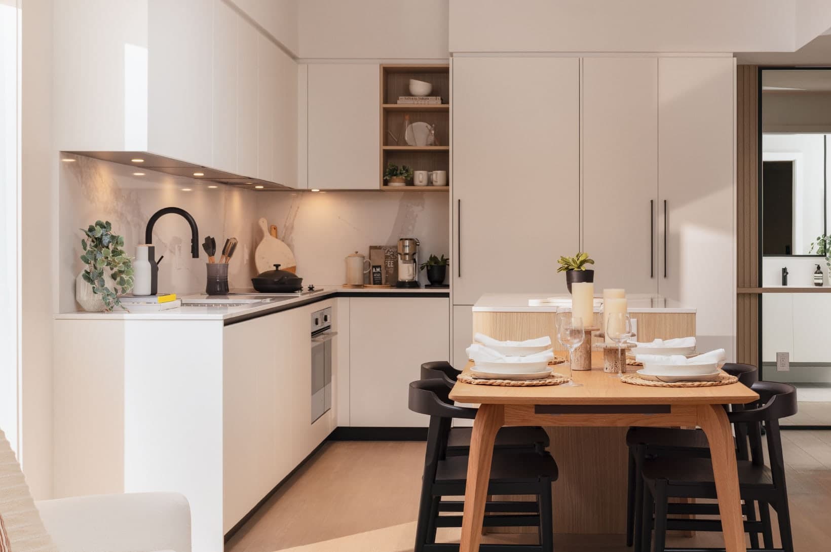 Umbra at Portwood – An open-concept kitchen and dining area featuring clean white cabinets, under-cabinet lighting, and an adjacent dining set.