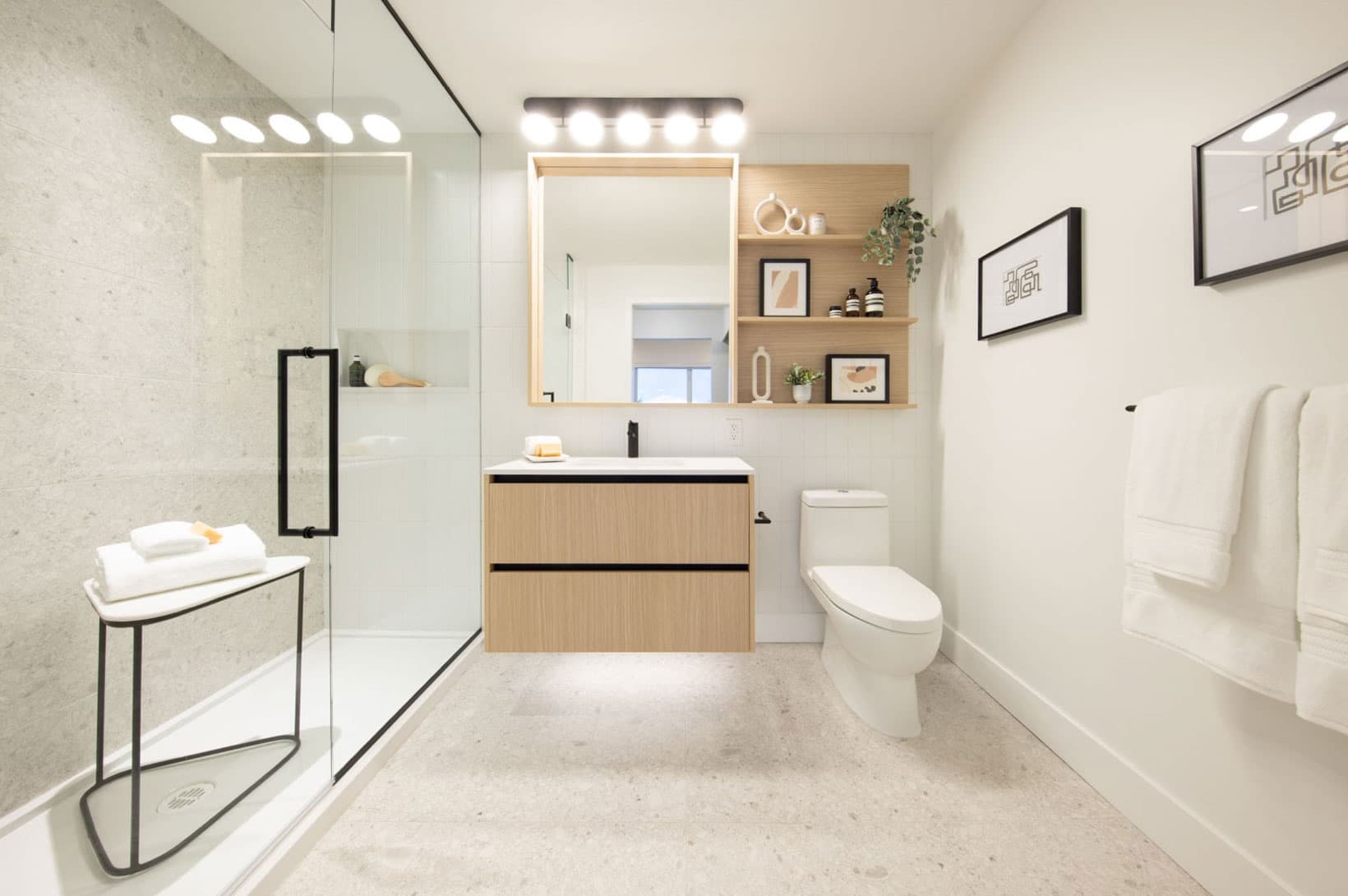 Umbra at Portwood – A modern bathroom featuring a floating wooden vanity, glass walk-in shower, and integrated wall shelving.