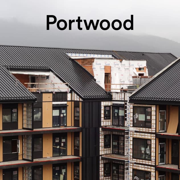 Umbra at Portwood – Mid-construction view of the multi-family residential building exterior with standing seam metal roofing and timber accents, labeled Portwood.