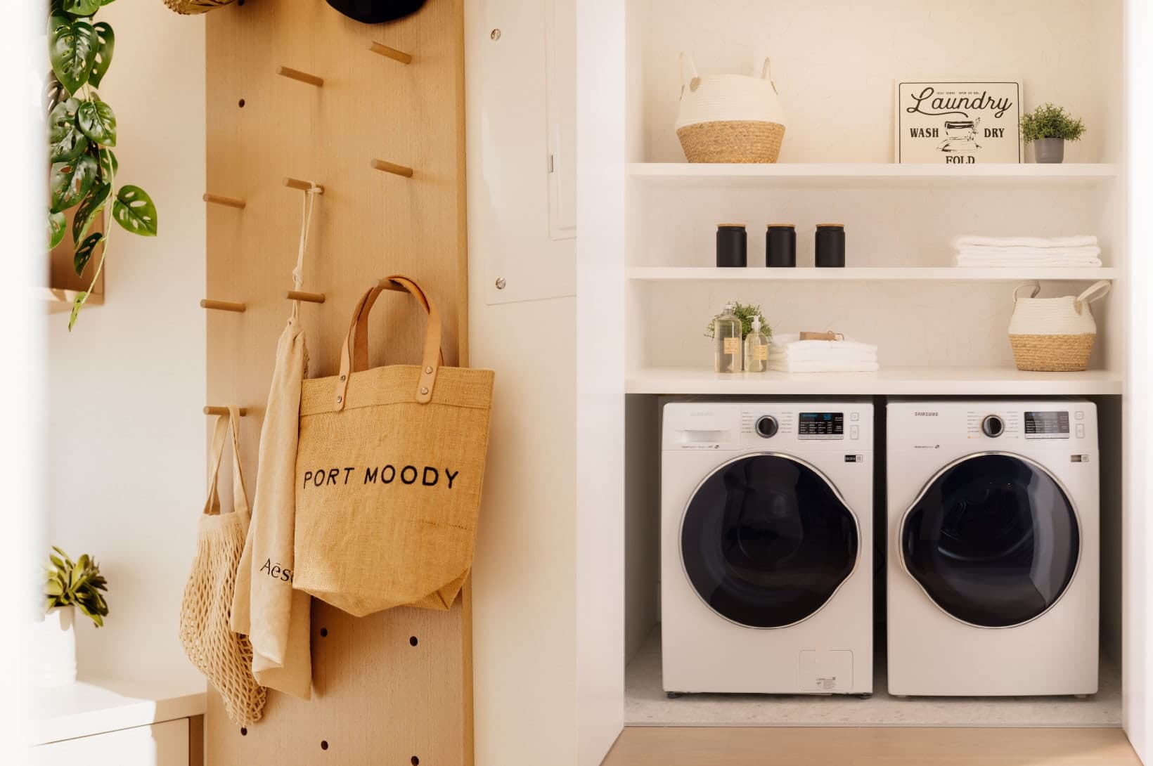 Umbra at Portwood – An entryway feature wall with pegboard hanging storage adjacent to a laundry closet with front-loading washer and dryer.