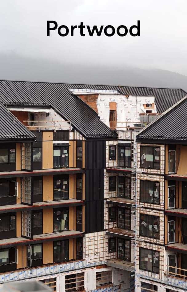 Umbra at Portwood – Mid-construction view of the multi-family residential building exterior with standing seam roofing and timber framing, labeled Portwood.