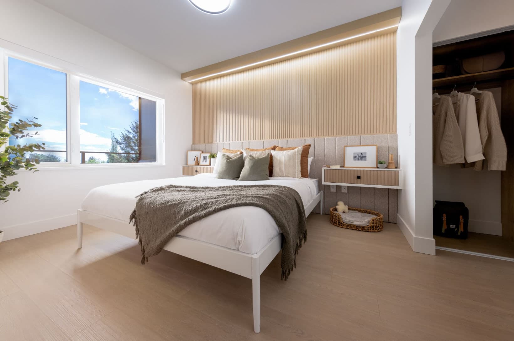 Umbra at Portwood – A primary bedroom featuring a wooden acoustic slat wall behind the bed, large windows, and a walk-in closet.