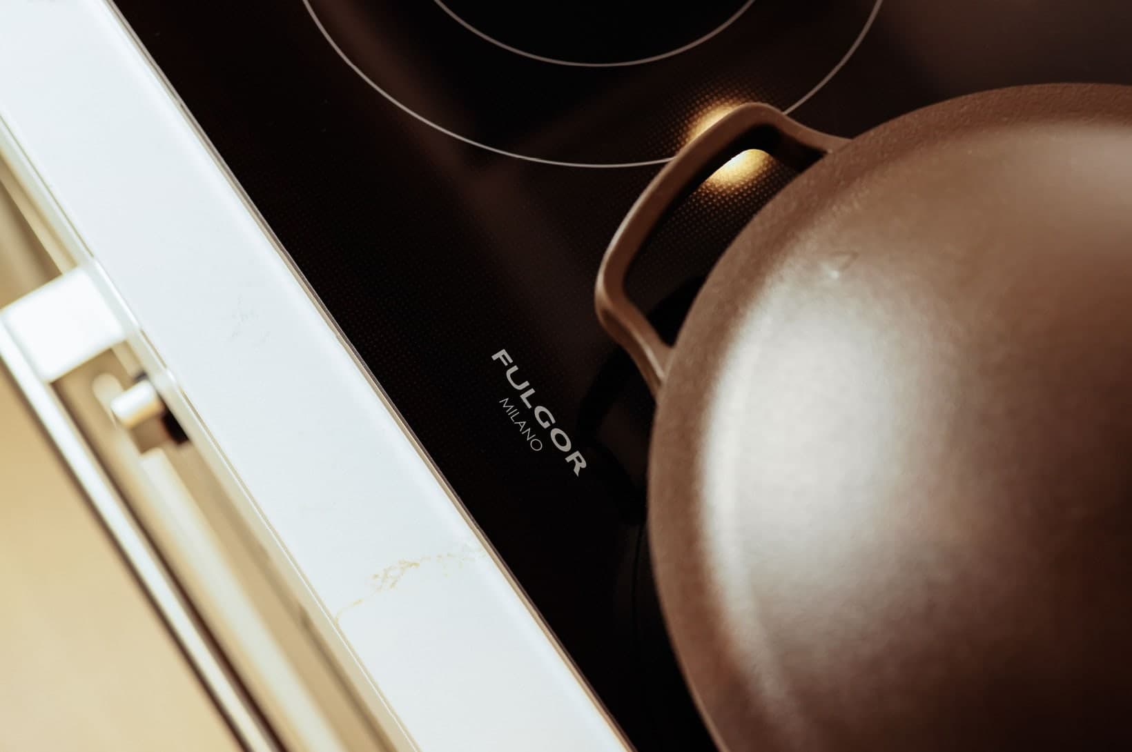 Umbra at Portwood – Close-up view of a Fulgor Milano glass cooktop surface with a cooking pot.