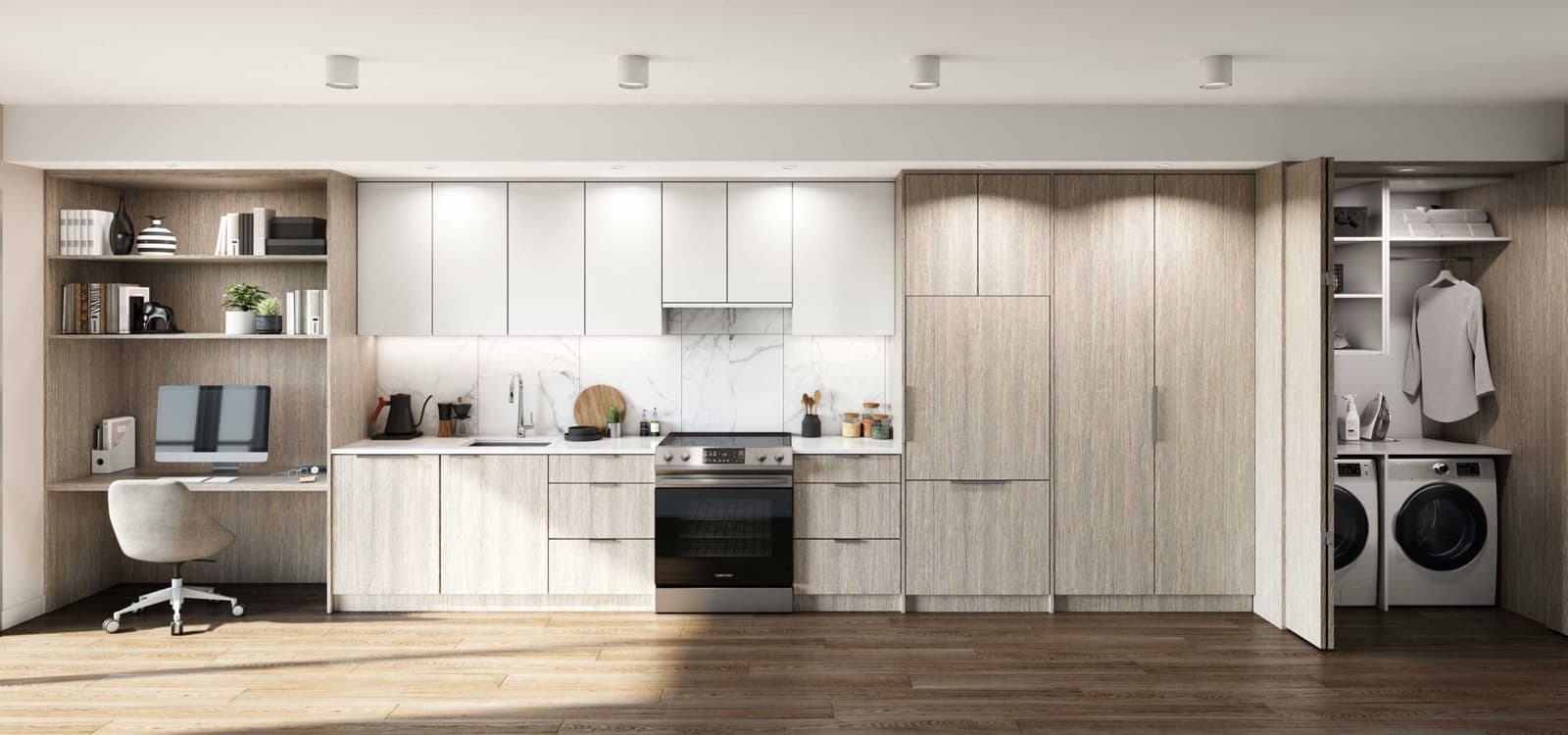 Sitka House – Kitchen with white upper cabinets and light wood lower cabinets next to a built-in home office desk and a folding closet with stacked washer and dryer.