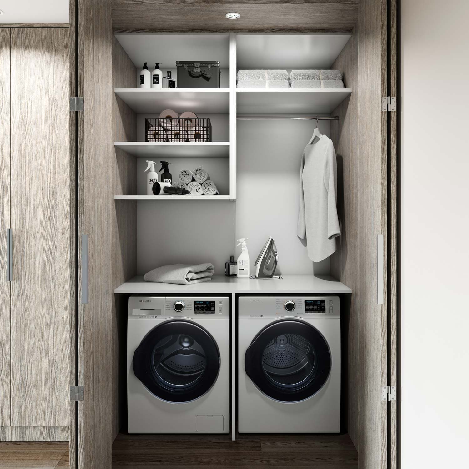 Sitka House – In-suite laundry closet with a stacked washer and dryer, folded towels, and hanging clothes on open shelving.