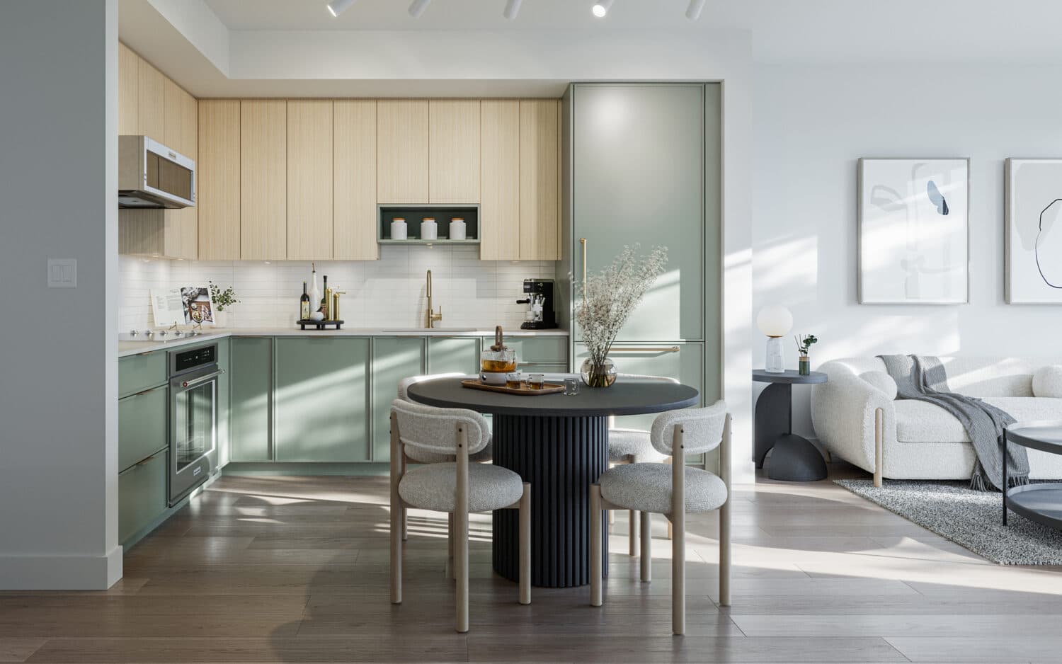 Emerald – A modern open-concept kitchen and dining area featuring sage green lower cabinetry paired with light wood upper cabinets and built-in appliances. In the foreground, a round ribbed black dining table surrounded by four upholstered chairs sits on light hardwood flooring, illuminated by natural sunlight streaming into the space.
