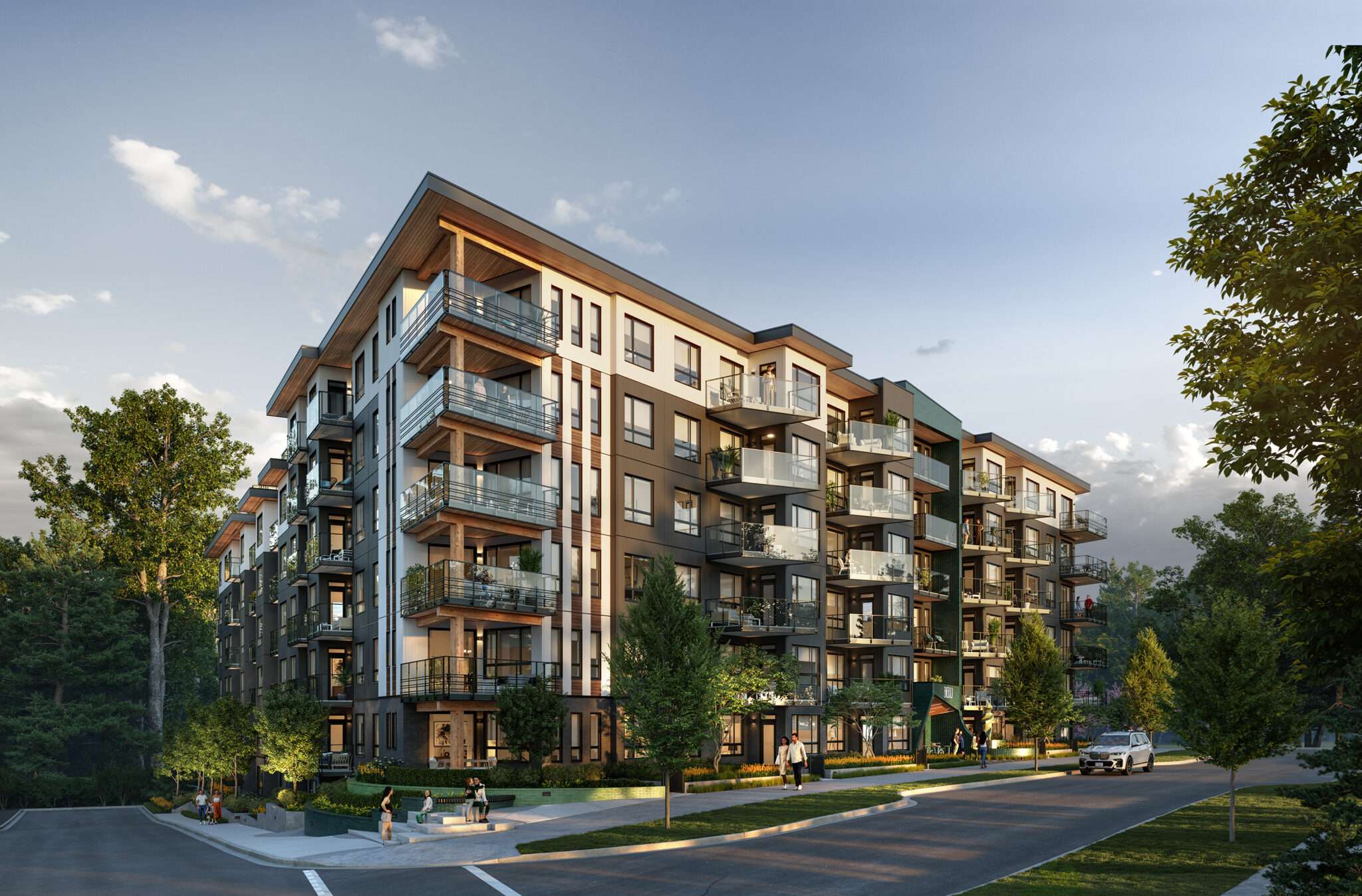 Emerald – A modern, six-story residential building features a mix of dark charcoal cladding, white accents, and warm wood soffits with private glass-railed balconies. Pedestrians walk along landscaped sidewalks with young trees in bright daylight under a clear blue sky.