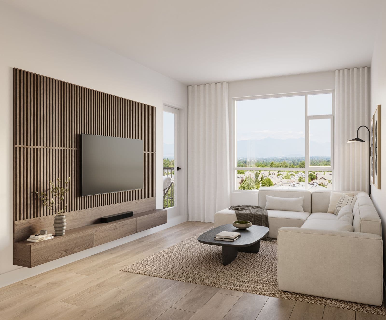 The Commons – Living room with a wood slat accent wall and mounted TV, a beige sectional sofa, dark round coffee table, and a large window overlooking mountains and rooftops.