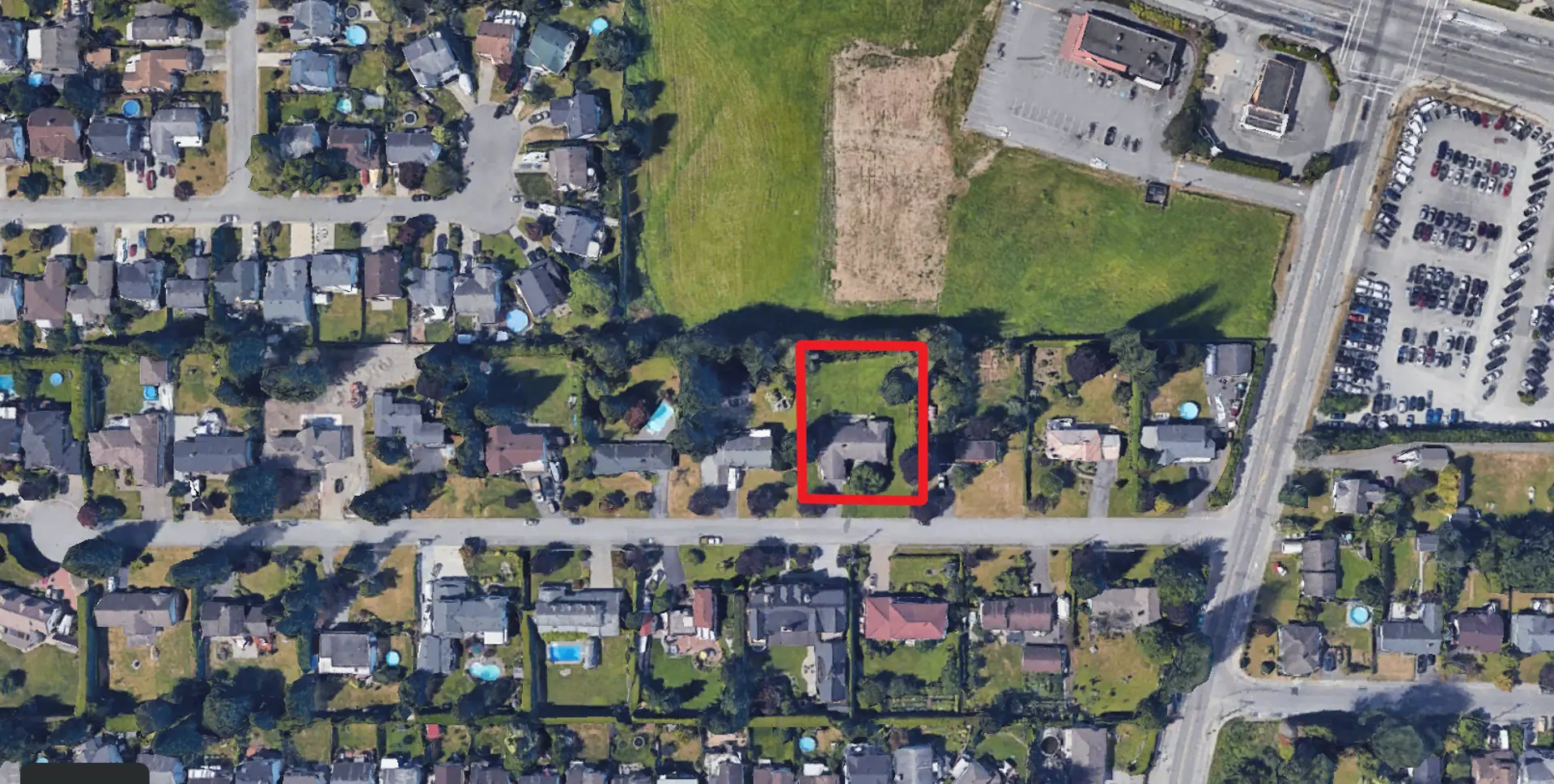 Patterson Ridge – This top-down satellite aerial view highlights a single-family residential property with a grassy yard outlined in a red box. The surrounding suburban neighborhood features streets lined with detached homes, adjacent green fields, and commercial parking lots to the northeast.