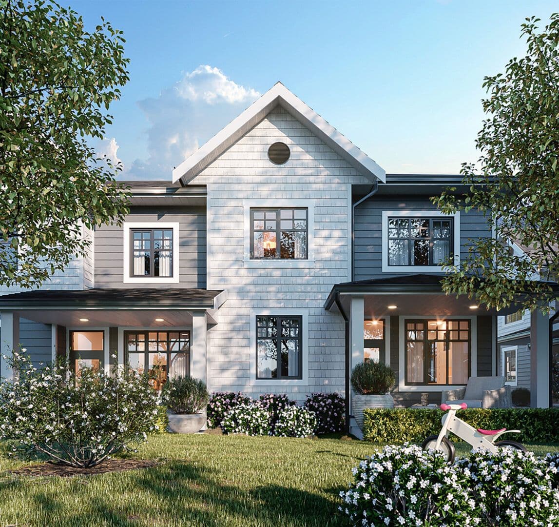 Newbury – Front exterior of a two-story townhome unit with grey and white shingle siding, gable roof, covered porch, and landscaped front yard with a child's balance bike.