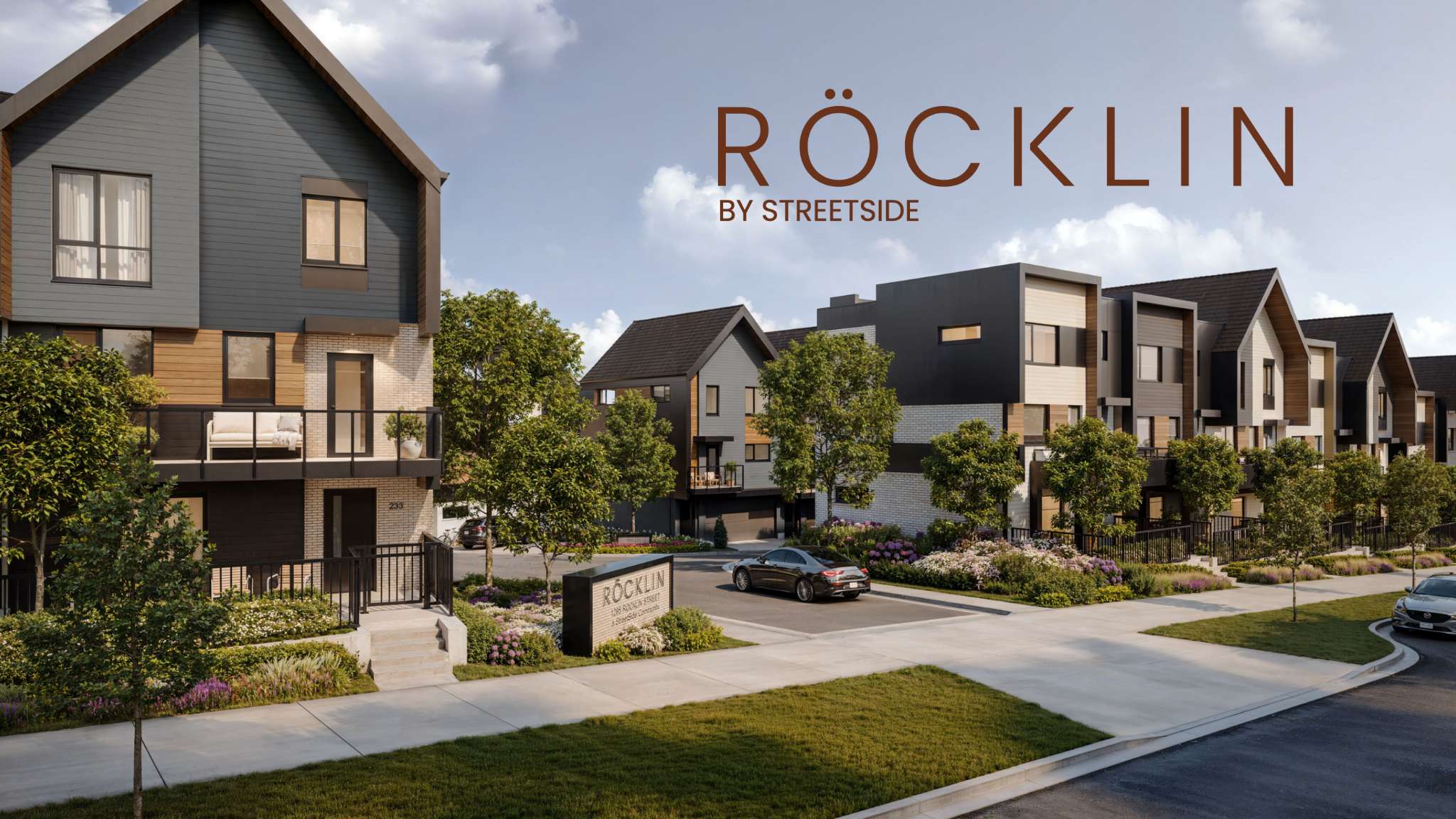 Rocklin – Rendered street view of the Rocklin by Streetside townhome community with a project sign, driveway, and landscaped entrance.