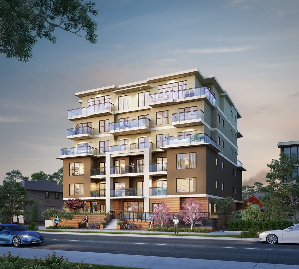 Estella – Twilight street-level view of a mid-rise apartment building with tan, brown, and dark cladding.