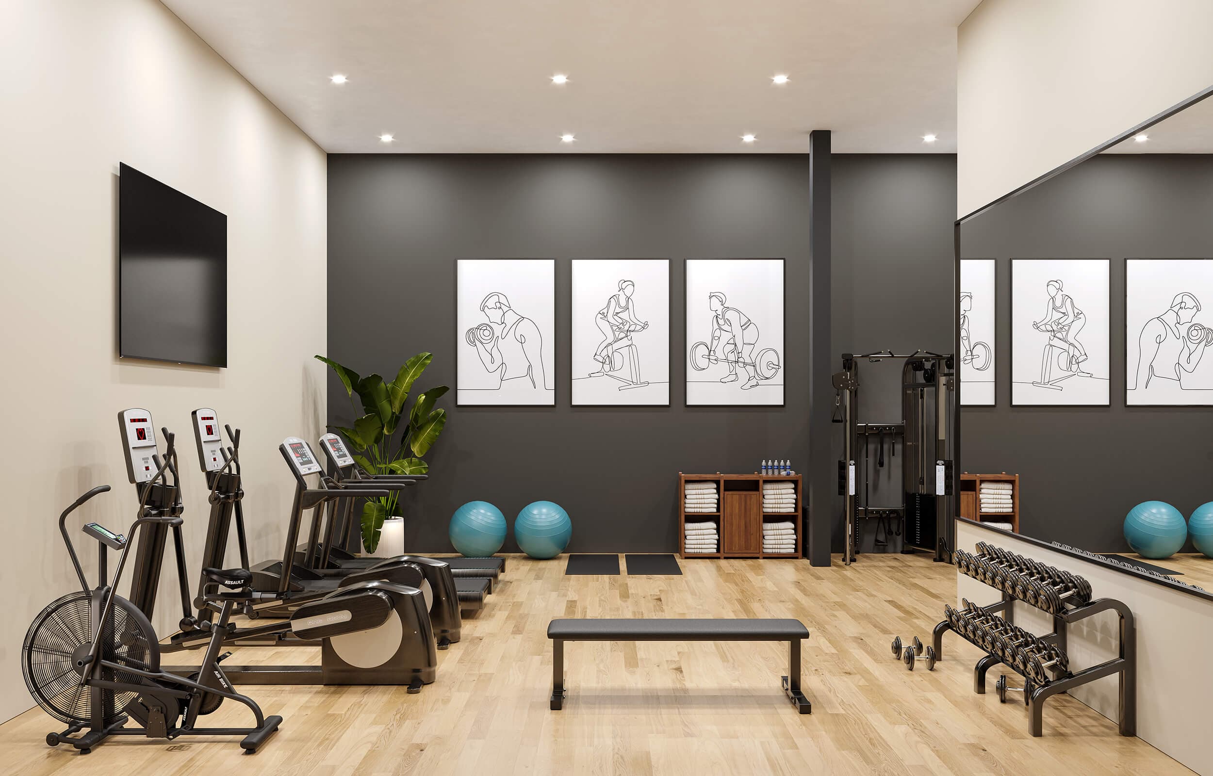 Stowa – A modern residential gym features light wood flooring, warm beige side walls, and a dark grey accent wall adorned with minimalist fitness artwork and a large mirror. The space is equipped with cardio machines like stationary bikes and treadmills, a free weight rack with dumbbells, a bench, yoga equipment, and a functional trainer tower.