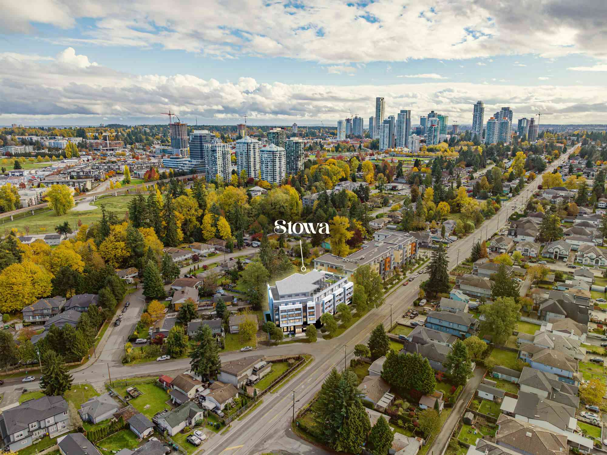 Stowa – An elevated drone perspective showcases a highlighted low-rise residential building surrounded by suburban streets and colorful autumn trees, with a modern city skyline visible in the background under a partly cloudy sky. The image features a prominent graphic pin labeled 'Stowa' pinpointing the development's location within the broader neighborhood.