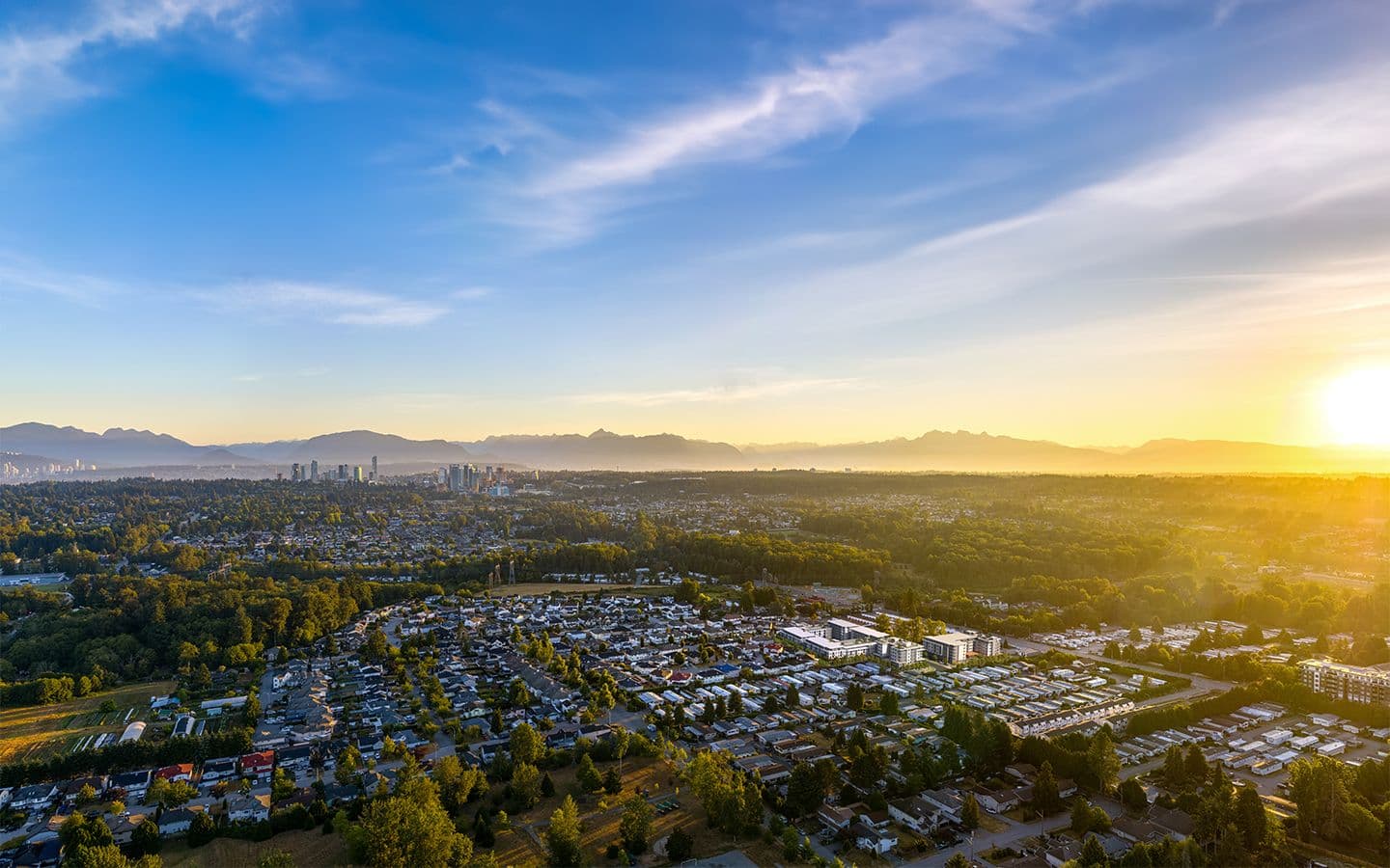 Spera – Aerial sunrise view from a slightly different angle showing the same mid-rise buildings within the neighborhood, with a distant downtown skyline and mountain range.