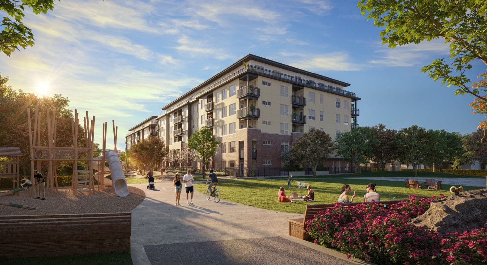 Ashton – A wood-tower playground and green lawn in front of the apartment building, with people walking, cycling, and picnicking at sunset.
