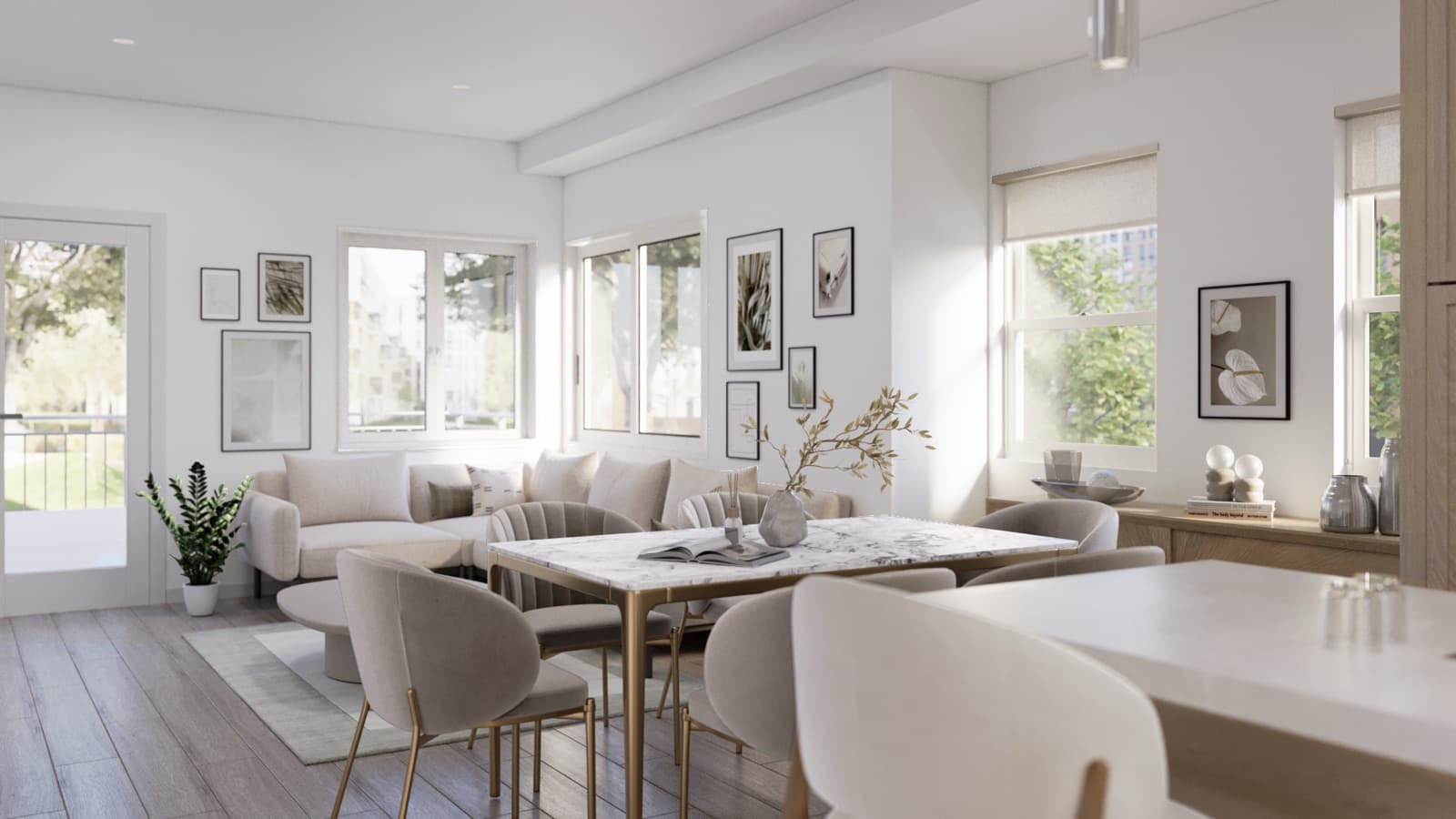 Compass Cohousing – Living room and dining area with a beige sectional sofa, gold-framed marble dining table, gallery wall of framed art, and windows overlooking a green courtyard.
