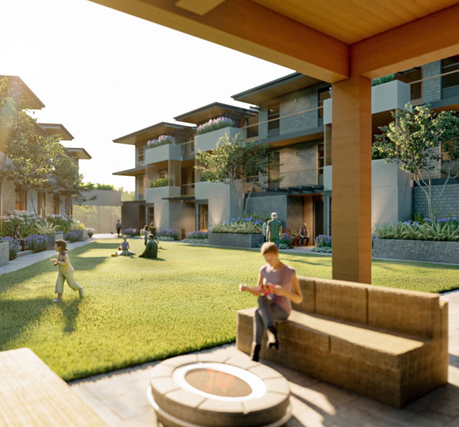 Compass Cohousing – Outdoor covered patio and lawn amenity area with a fire pit, wicker bench seating, and residents including children playing on the grass at golden hour.