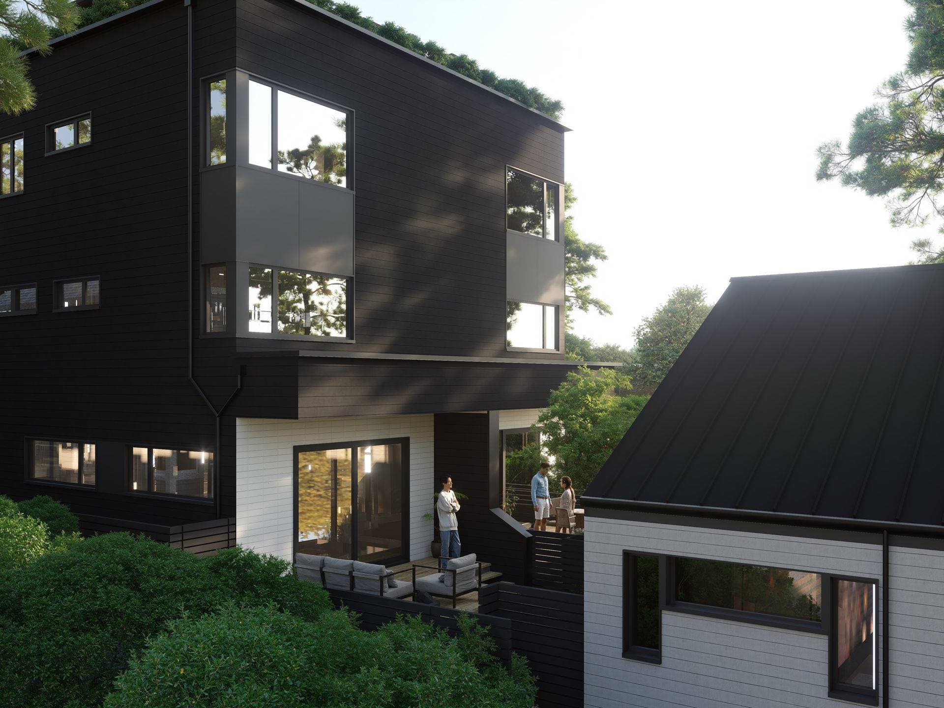 The Park Residences – An elevated view of modern residential townhomes featuring bold black and off-white horizontal siding, dark metal roofing, and large corner windows. People are gathered on private outdoor patio decks furnished with seating and surrounded by lush green trees in soft daylight.