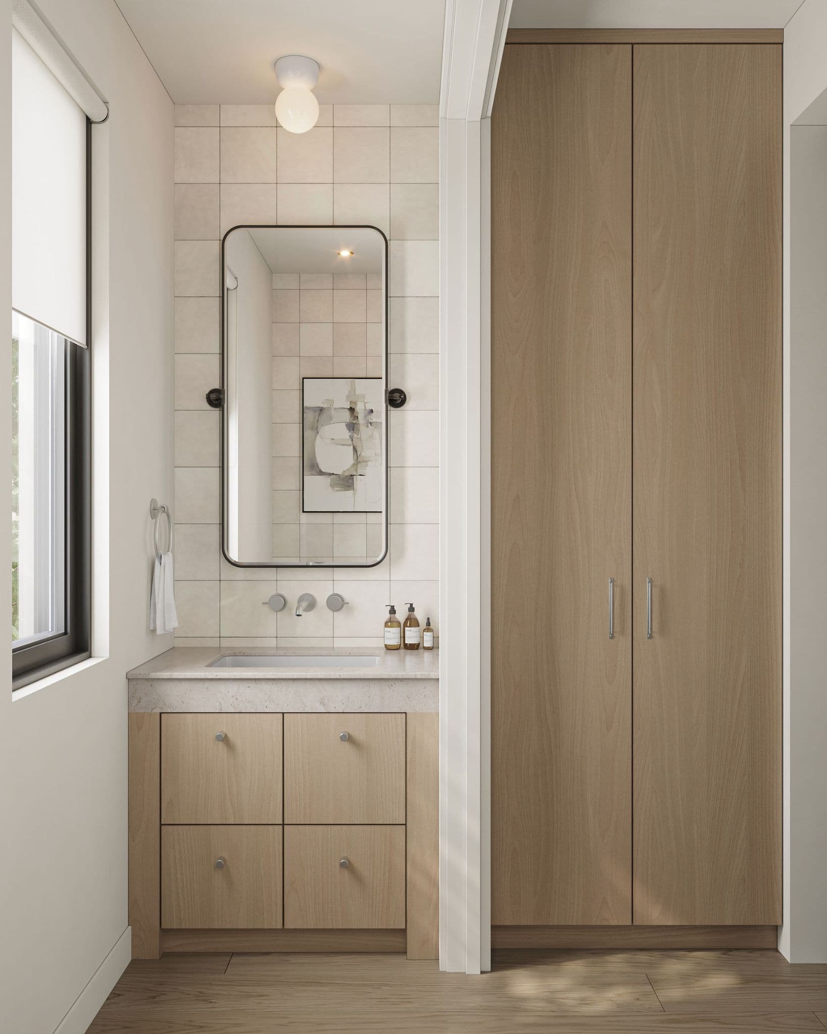 The Park Residences – A bright, minimalist bathroom vanity nook featuring light wood cabinetry, stone countertops, and off-white square wall tiles. A tall wooden linen cabinet stands adjacent to the sink, which is accessorized with a black-framed pill-shaped mirror and polished chrome fixtures beneath soft natural light.