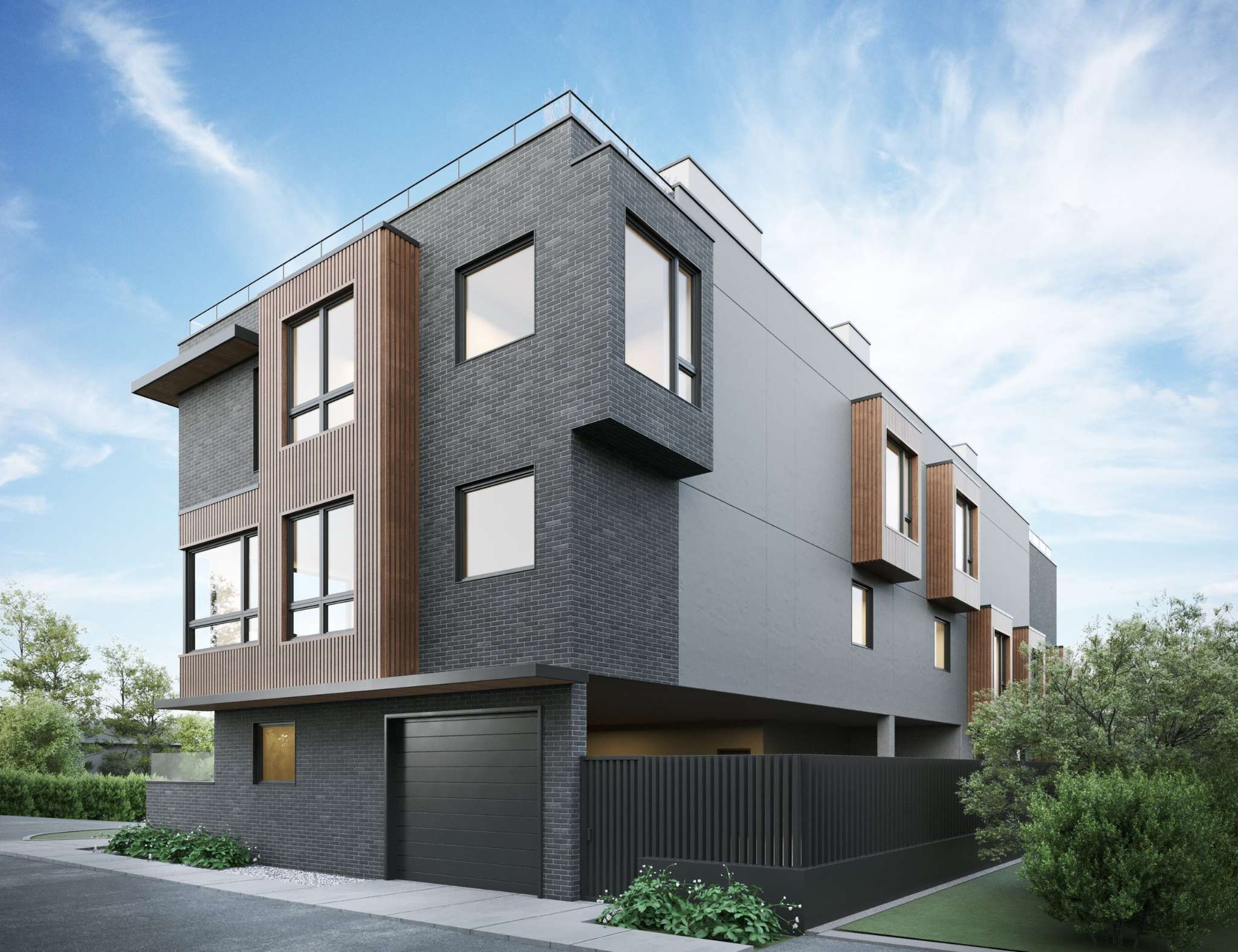 The Vantage – An architectural rendering of a modern three-story multi-family townhouse corner, featuring a mix of dark charcoal brick, smooth gray panels, and vertical warm wood slat accents framing large windows. A dark garage door and black vertical slat fence line the ground level, bordered by neat landscaping and a clear blue sky with light wispy clouds.
