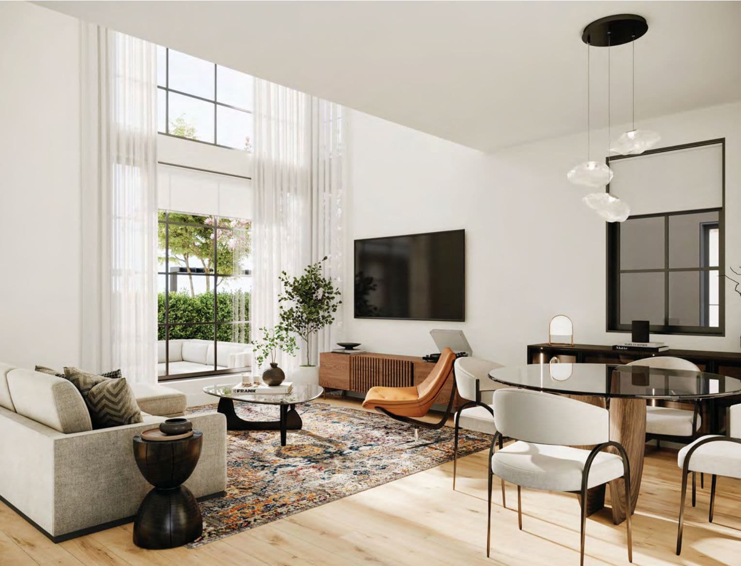 The Edgemont Collection – A double-height living and dining room with sheer curtains, a beige sofa, round glass coffee and dining tables, an orange accent chair, and a wall-mounted TV.