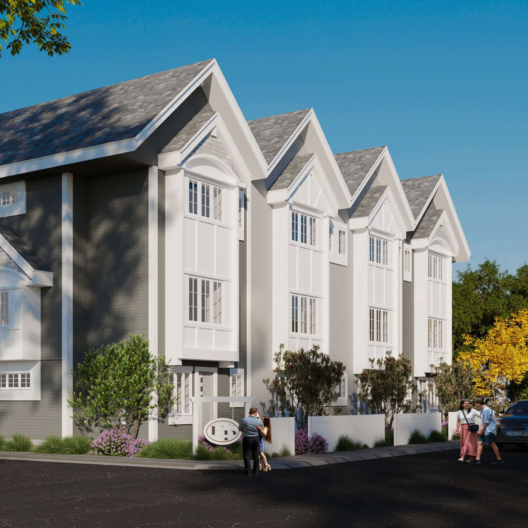 Flavelle Place – A low-angle exterior view showcases a row of modern grey and white gabled townhomes with white trim and large multi-pane windows under a clear blue sky. People are seen walking along the front paved area near landscaped bushes, low white fences, and a community signage post.