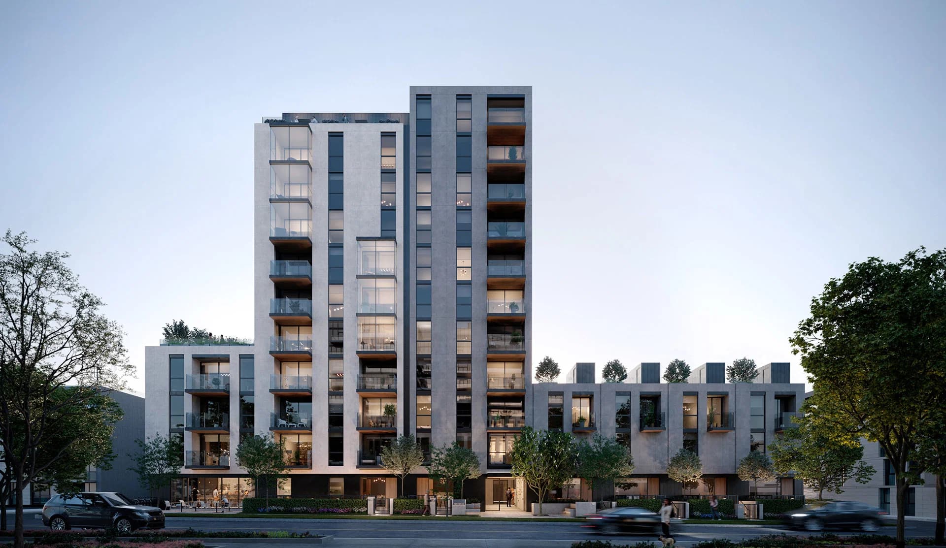 FORM – A modern, mid-rise residential building with light gray stone facades and large floor-to-ceiling windows framed by dark trim. The building features step-down side wings, glass-railed balconies with rooftop greenery, street-level landscaping, and cars passing along a quiet city street under a soft dusk sky.