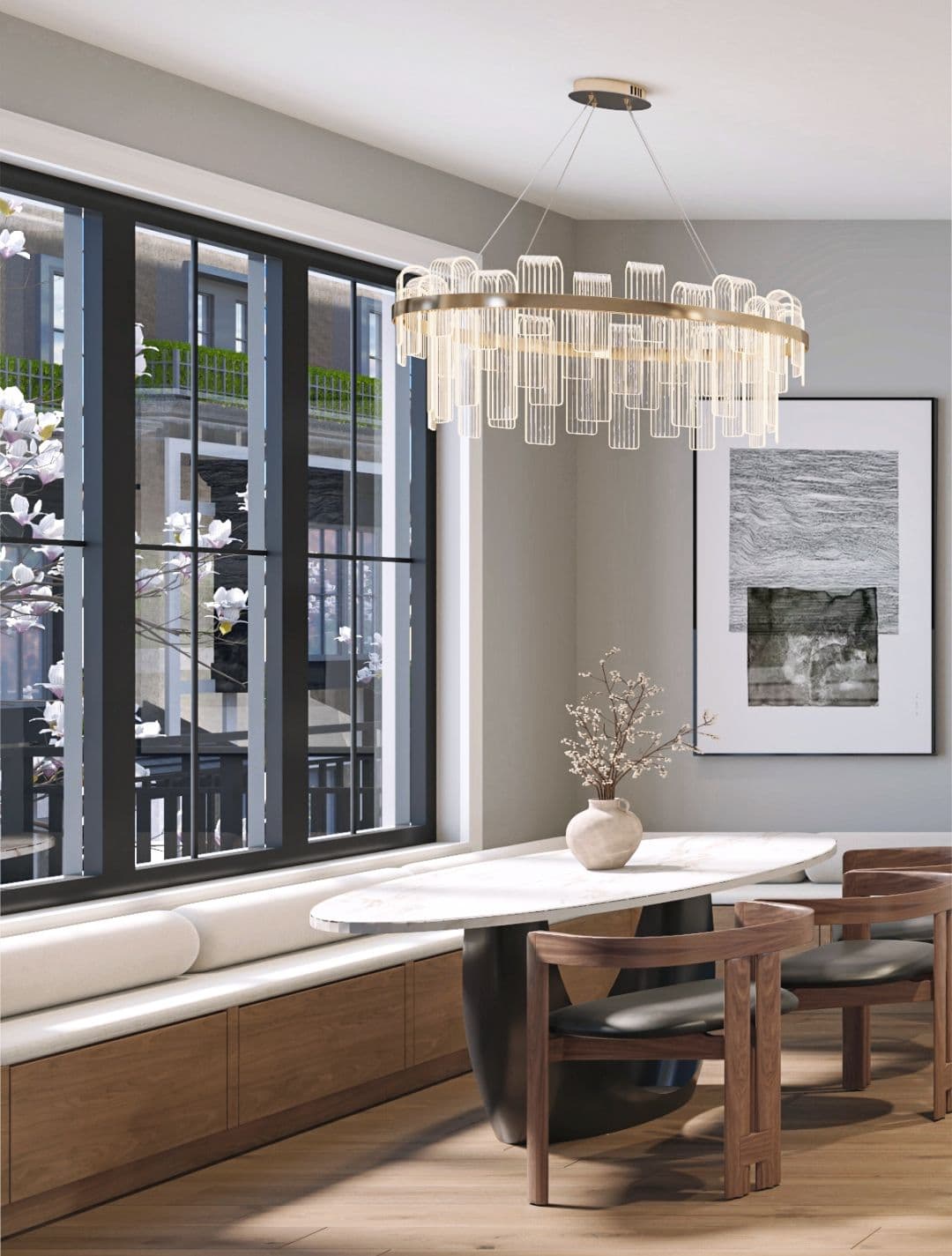 Claremont – A modern dining nook features an oval marble-topped table, curved wood chairs, and a built-in banquette under large black-framed windows. An ornate gold-and-glass chandelier hangs above, with natural daylight illuminating the neutral walls and wood floors.