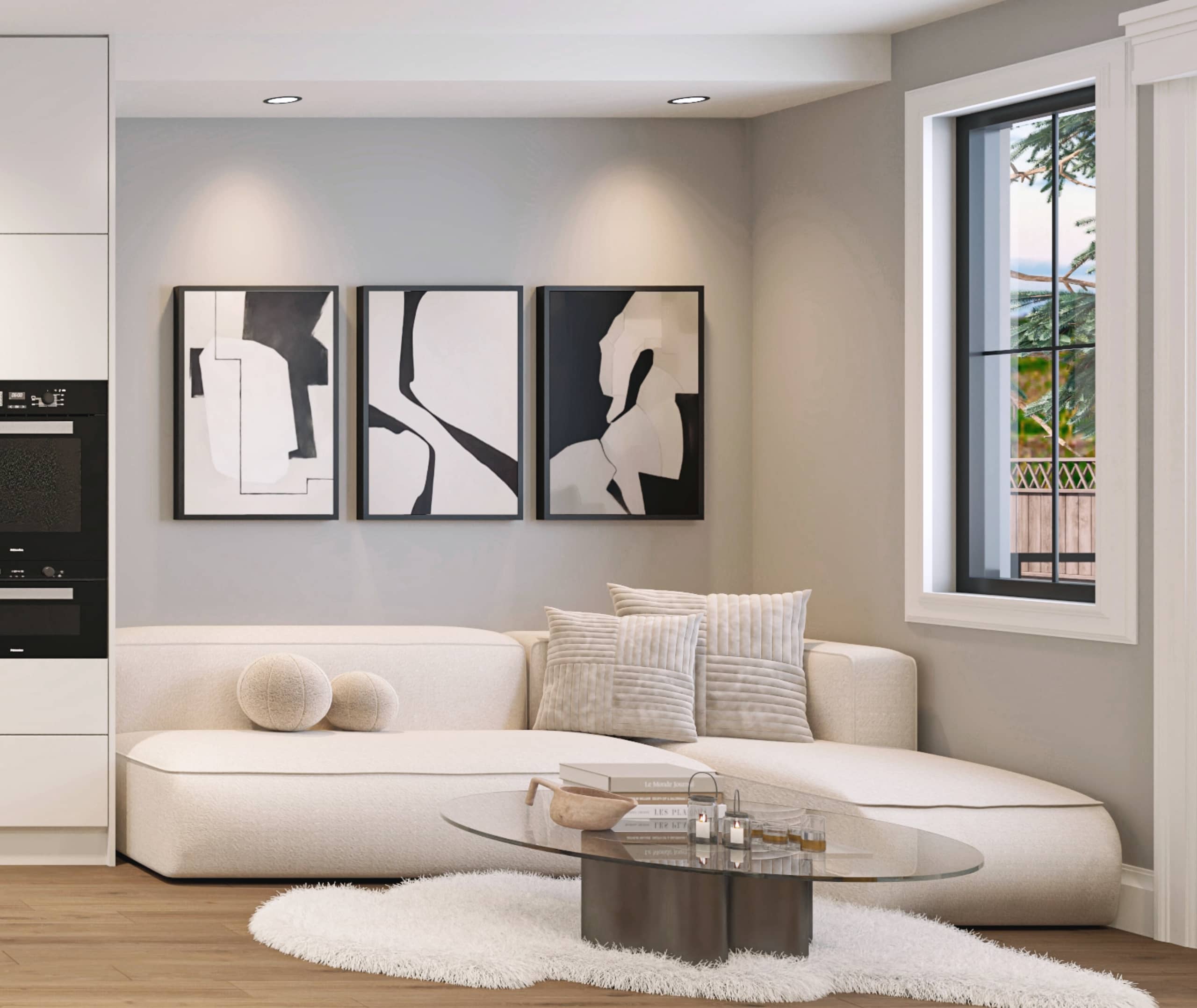 Claremont – A modern living room featuring a curved cream-colored sectional sofa paired with an oval glass coffee table atop a white shag rug. Spotlights highlight a triptych of abstract black-and-white art on a soft grey wall, adjacent to a window looking out onto outdoor greenery.