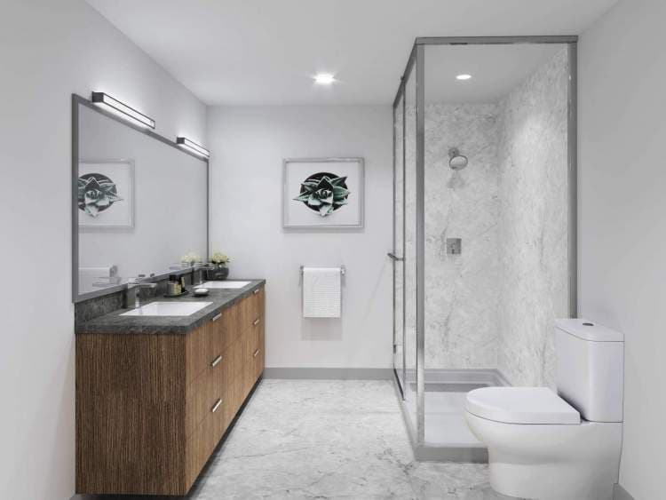 The Ridge – Bathroom rendering with a dark wood double vanity, dark stone countertop, large mirror, and a glass-enclosed marble-tiled shower next to the toilet.