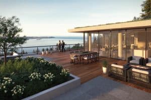 Courtenay at Mulgrave Park – Rooftop terrace with wood decking, outdoor lounge seating and dining table, planters, and a wide view over water and mountains at sunset.